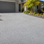 Light grey resurfaced exposed aggregate driveway on the Gold Coast, finished with a textured spray-applied coating.