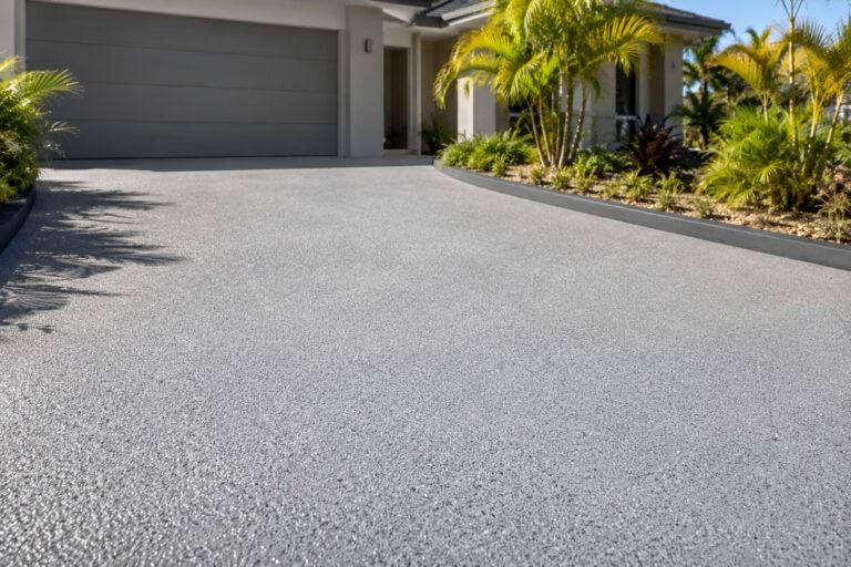 Light grey resurfaced exposed aggregate driveway on the Gold Coast, finished with a textured spray-applied coating.